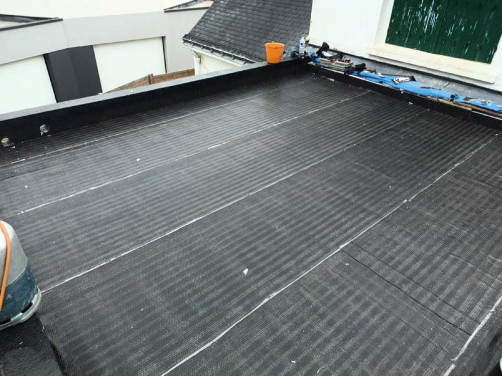 Artisan couvreur rénovant un toit plat à Nœux-les-Mines